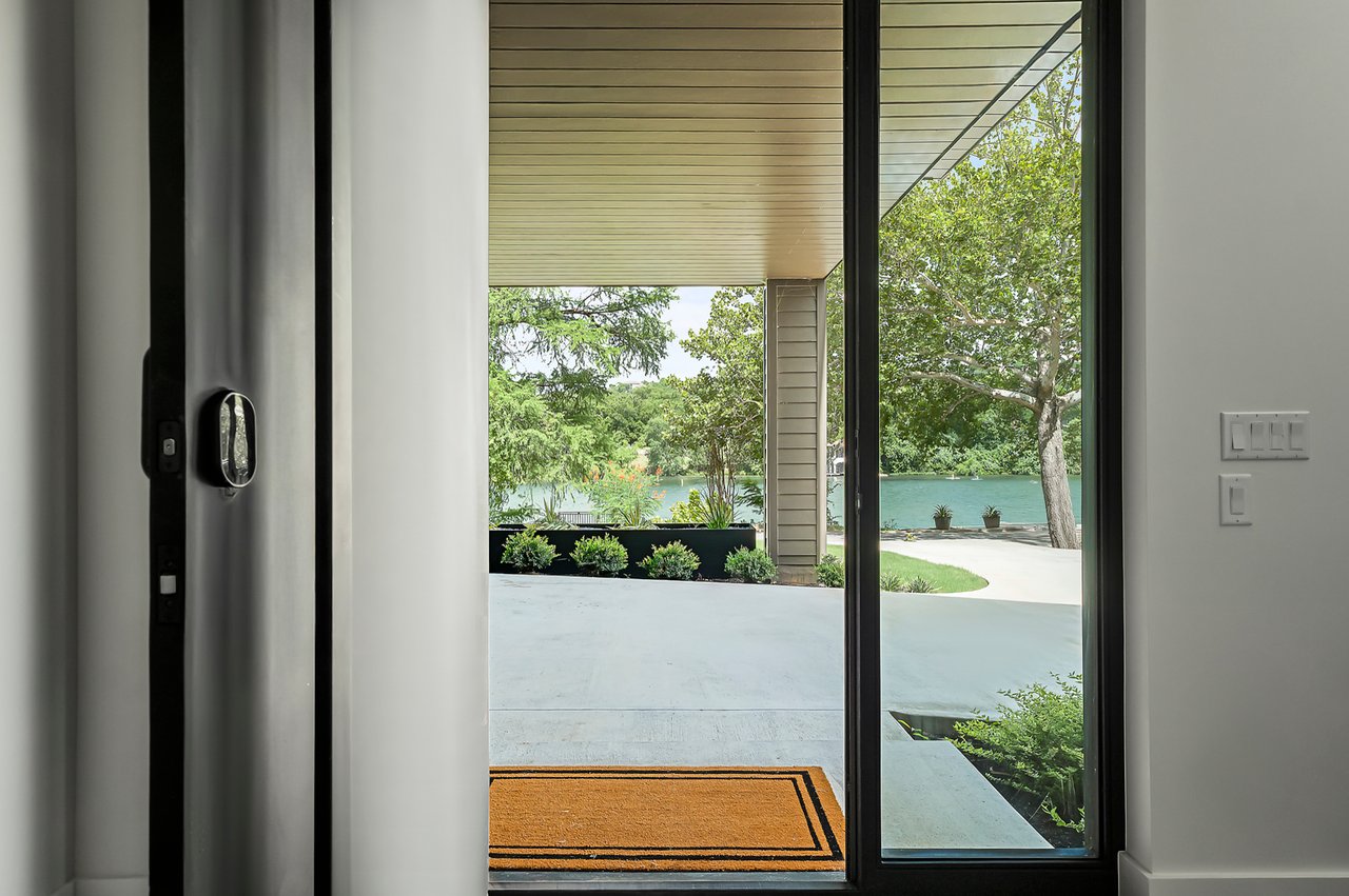 Entry door framing a Lake Austin view under a wood plank ceiling, designed by Kelley Design Group and built by Pecan Valley Custom Homes at 2403 Big Horn Drive, Austin.