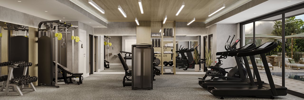 Modern residential gym with treadmills and weight machines beside glass doors opening onto a landscaped patio.