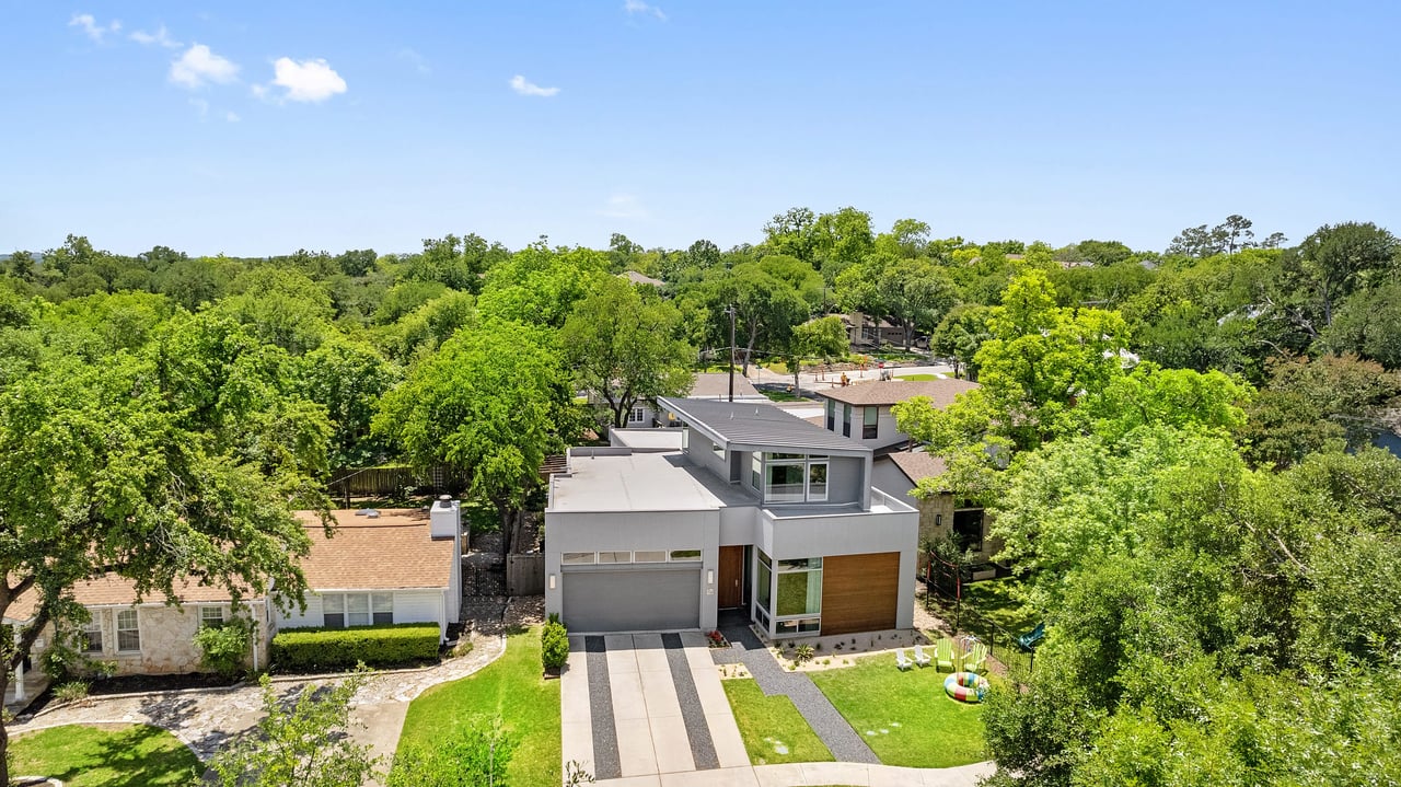 Aerial view of the front exterior of 34 Margranita Crescent, Tarrytown, Austin, TX, surrounded by mature tree canopy.
