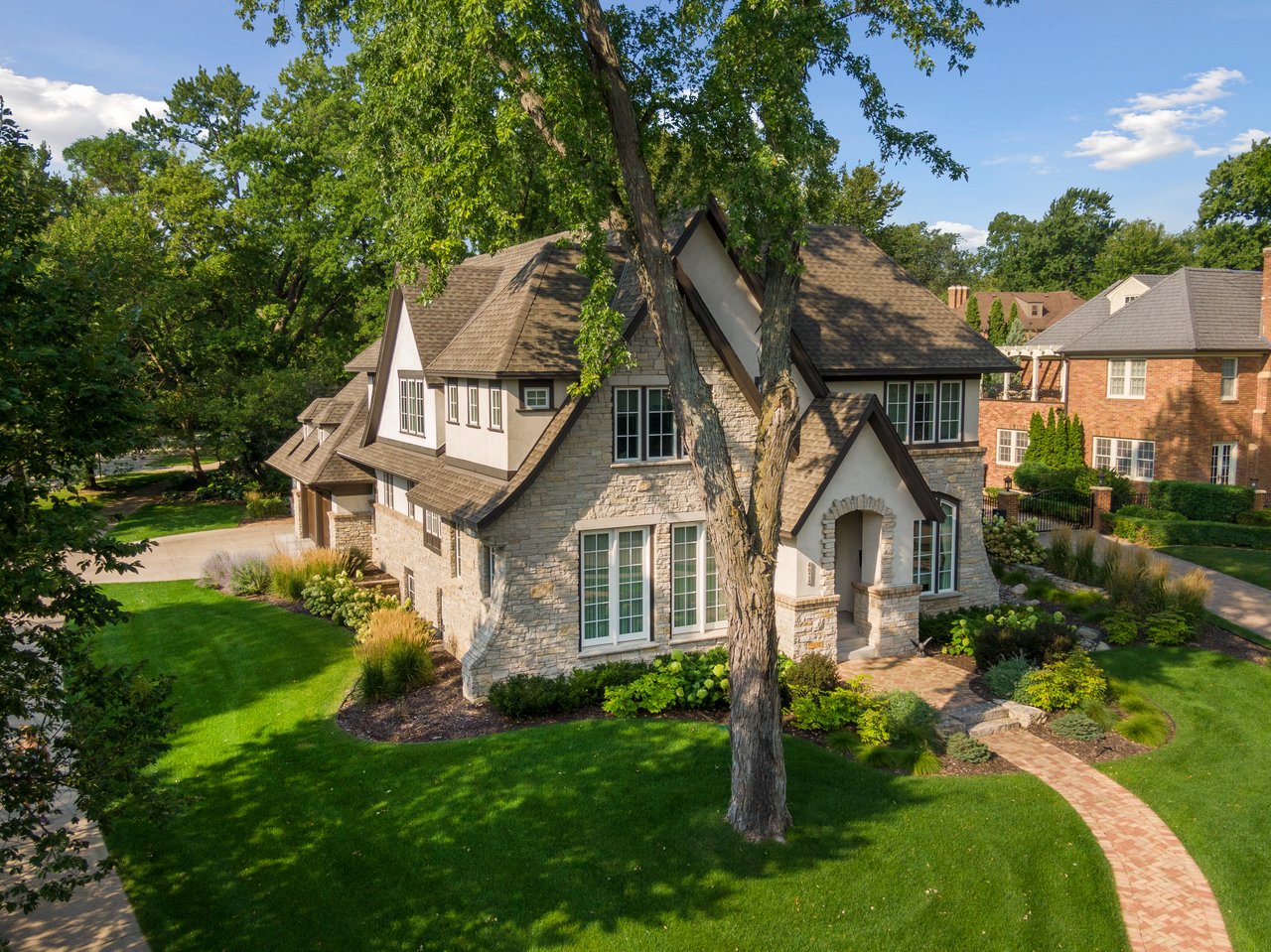 An aerial view of a luxury Tudor style home with stone accents and a manicured green lawn in the historic Country Club neighborhood of Edina, Minnesota, represented by the Cari Ann Carter Group.