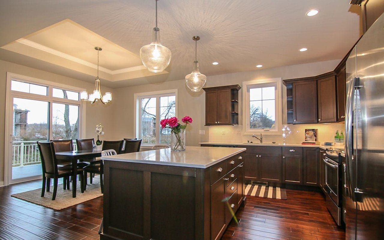 Kitchen with a large island, dark wood cabinetry, and an adjacent dining area beside deck doors.