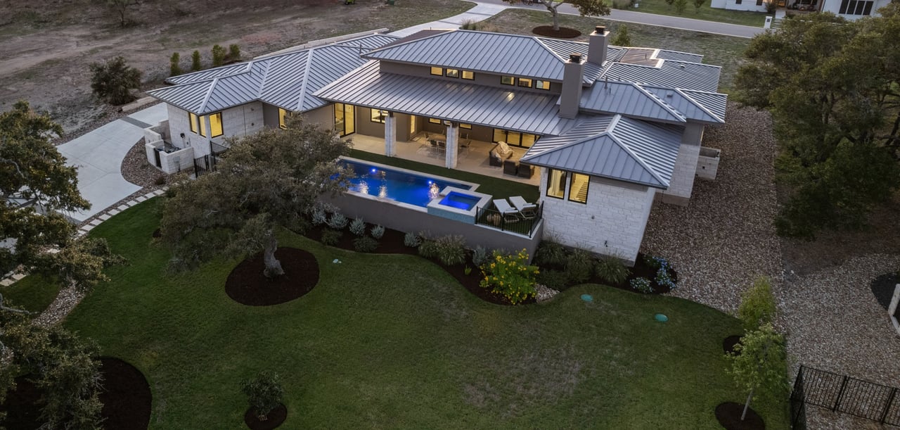 Twilight aerial view of the single-story home and pool at this Caudill Lane property in the Bee Caves area of Austin, Texas.