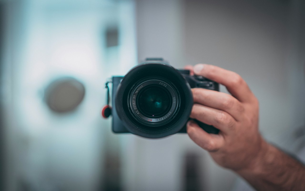 A hand holds a camera with a large lens.