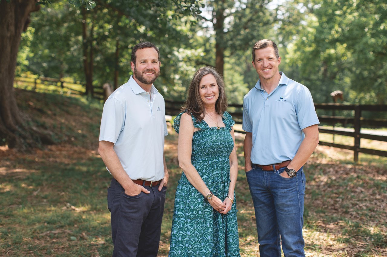 Three Candler team members pose outdoors, with two men in branded polos flanking a woman.