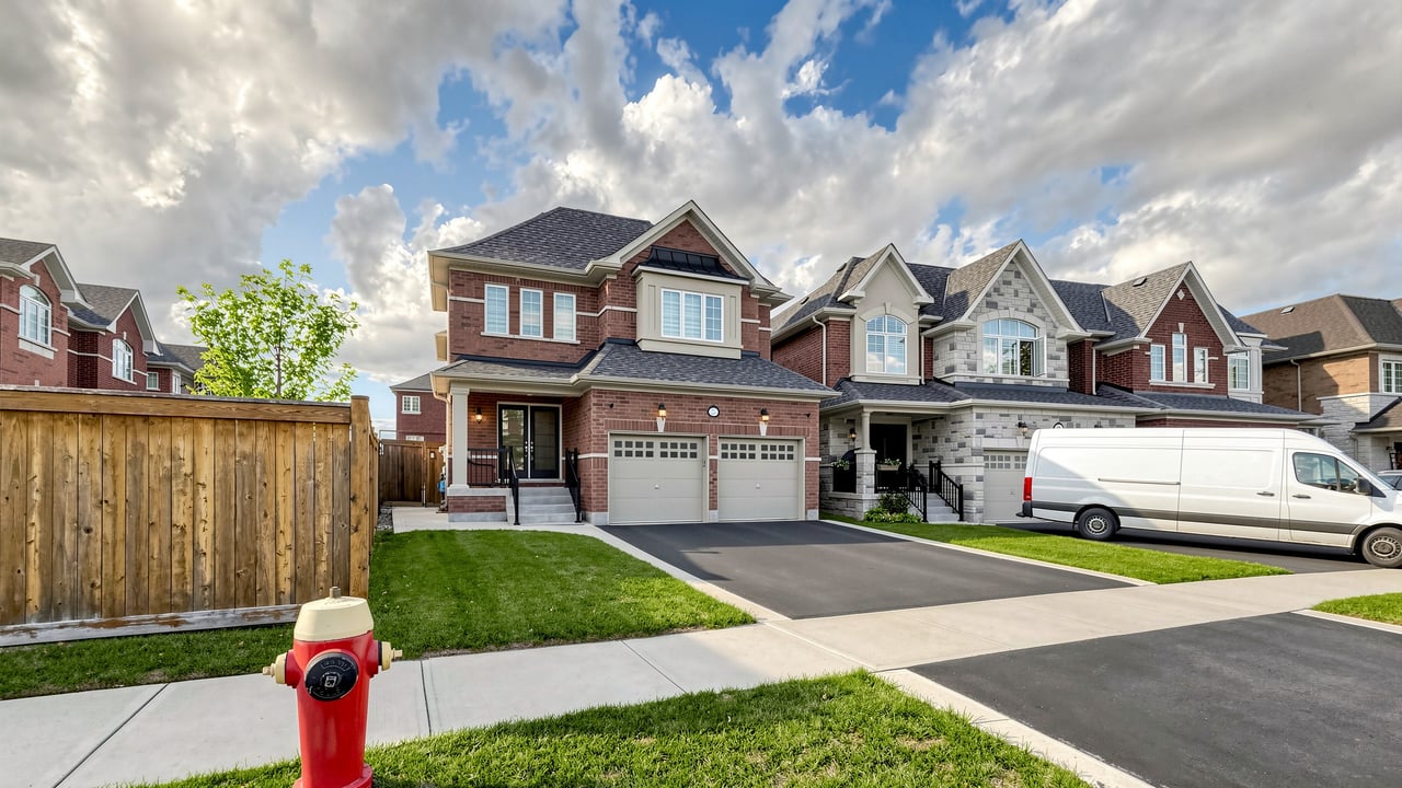 Two-story brick house with a double garage, front lawn, and wide driveway.