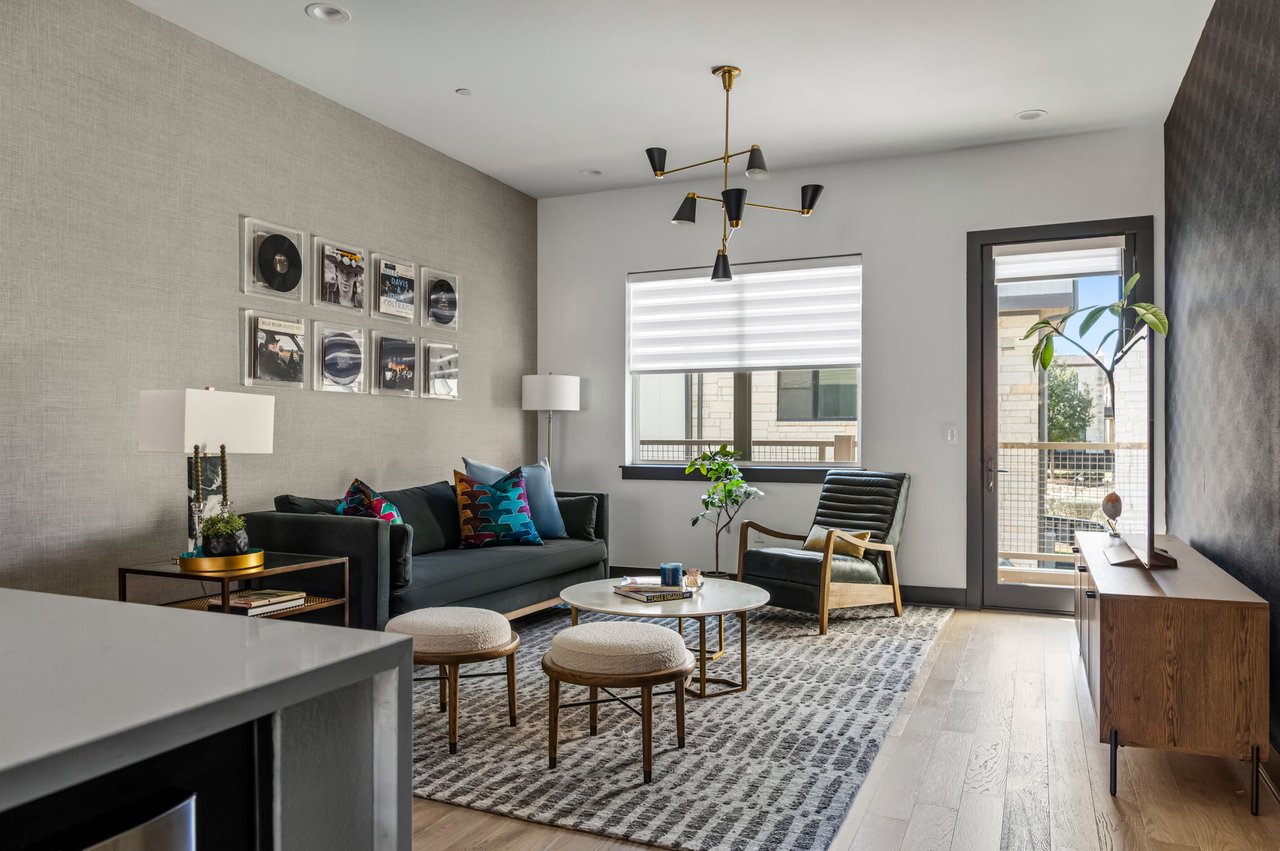 Living room at 4507 Unity Circle in The Grove, Austin, featuring a sculptural black and brass chandelier, layered gallery wall, and patterned area rug, designed by Ashley Walker Designs.