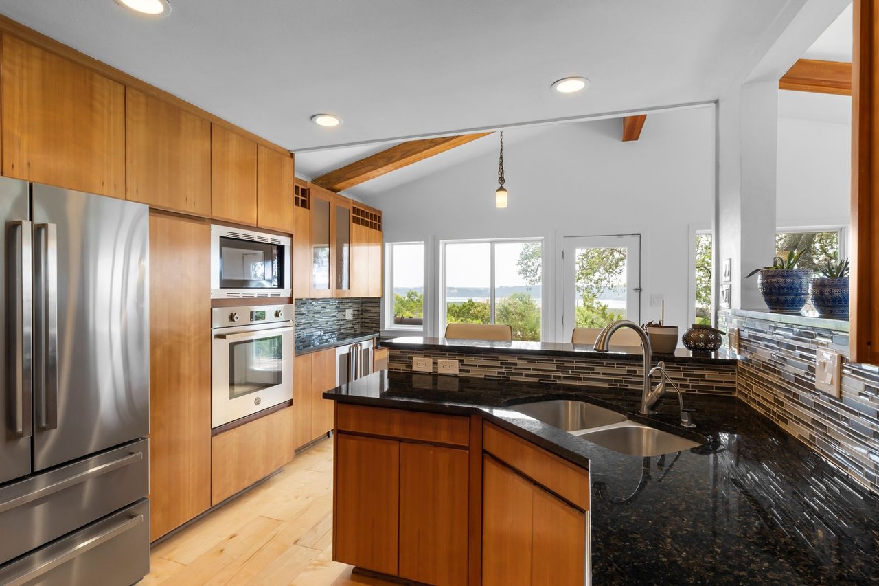 Kitchen with stainless double ovens, French-door refrigerator, and vaulted beamed ceiling at 3935 Lago Vista Drive, a hilltop Mid-Century Modern home overlooking Lake Travis, Austin, TX.
