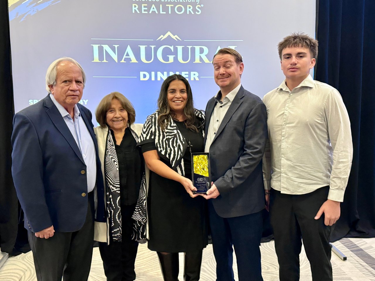 Giovanna Kennedy and four others pose with a trophy at an inaugural dinner.