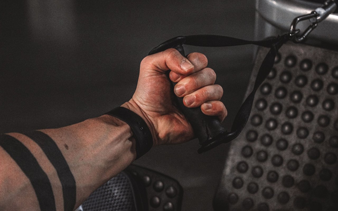 A tattooed arm grips a cable machine handle during a workout.