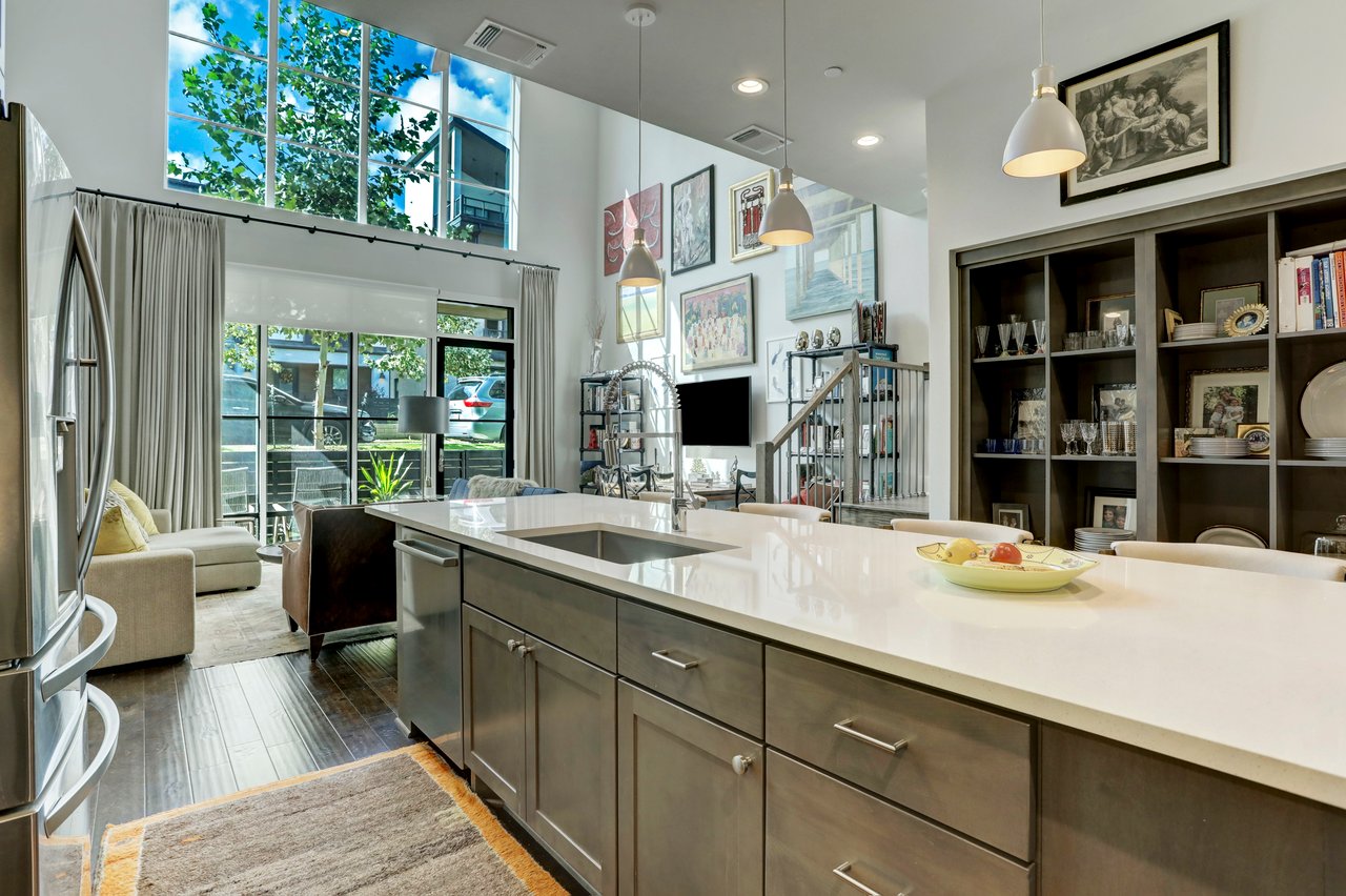 Kitchen view at 4709 Unity Circle, The Grove, Austin, TX, showing the eat-in waterfall island, cathedral ceiling, and floor-to-ceiling windows.