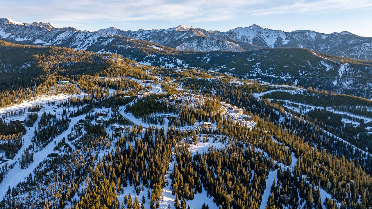 Cascade Ridge neighborhood nestled among snowy evergreen forests beneath a mountain range.