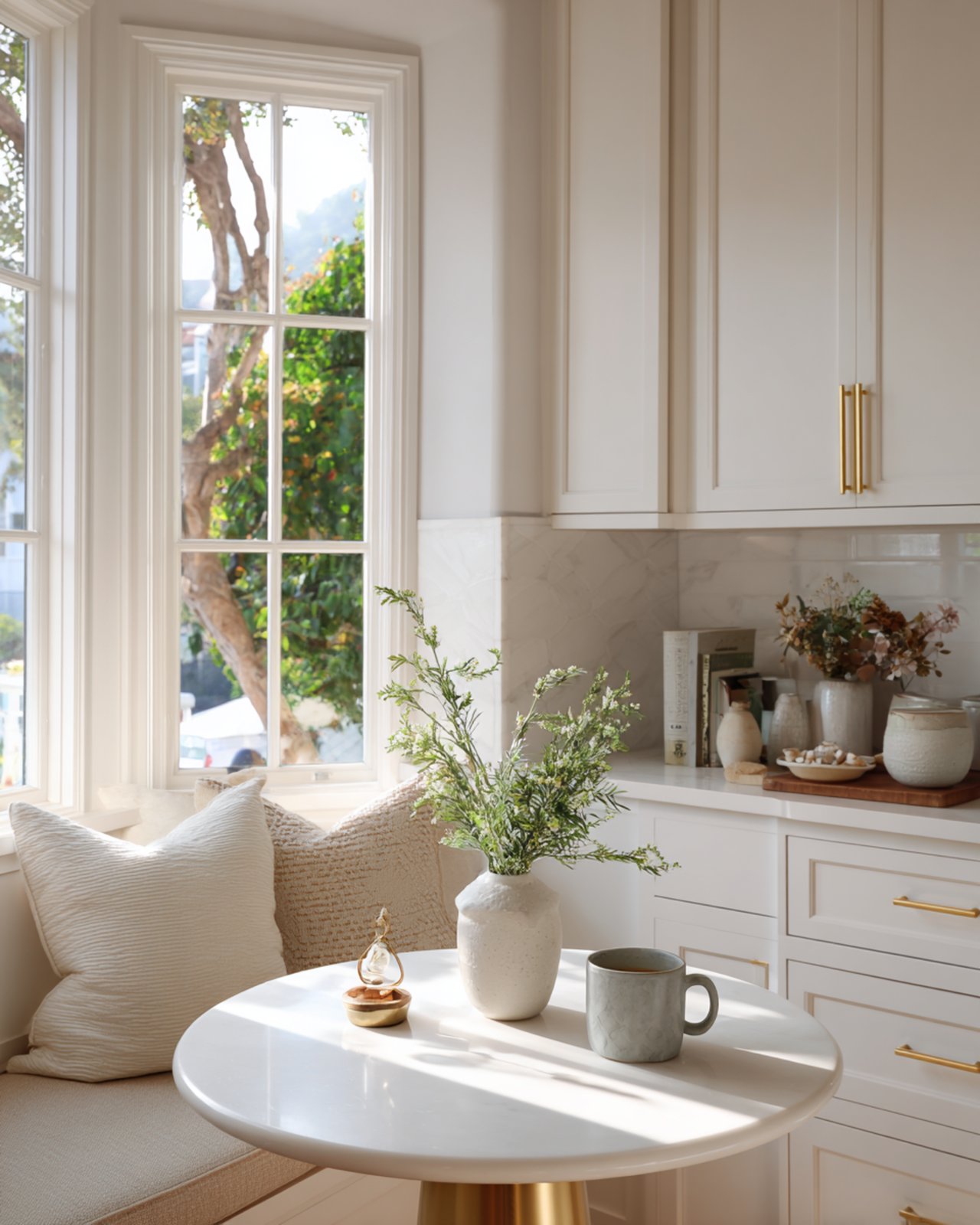 Kitchen breakfast nook with a round table, cushioned seating, and tall windows.