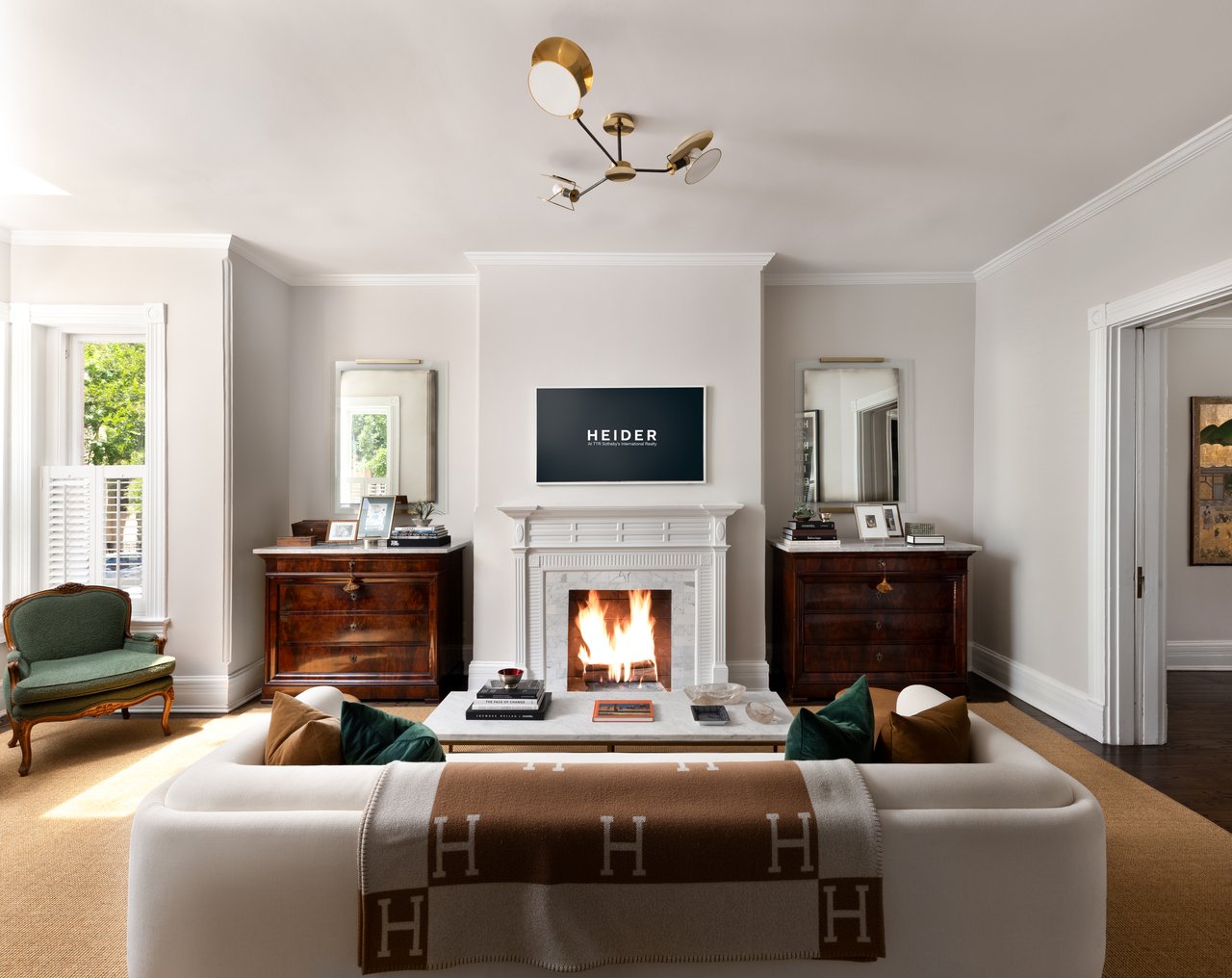 Living room with a lit fireplace, matching wood chests, and a white sofa with a patterned throw.