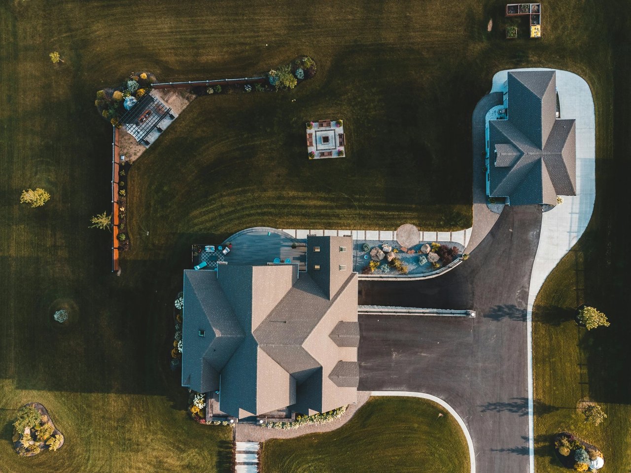 Aerial view of a large home property with landscaped lawns, patios, and a curved driveway.