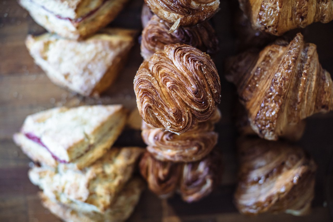Assorted golden pastries, with a large spiral pastry centered among elongated pastries and filled slices.
