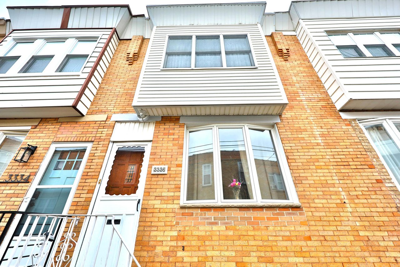 Brick row house with white-sided bay windows and front entrance numbered 3336.