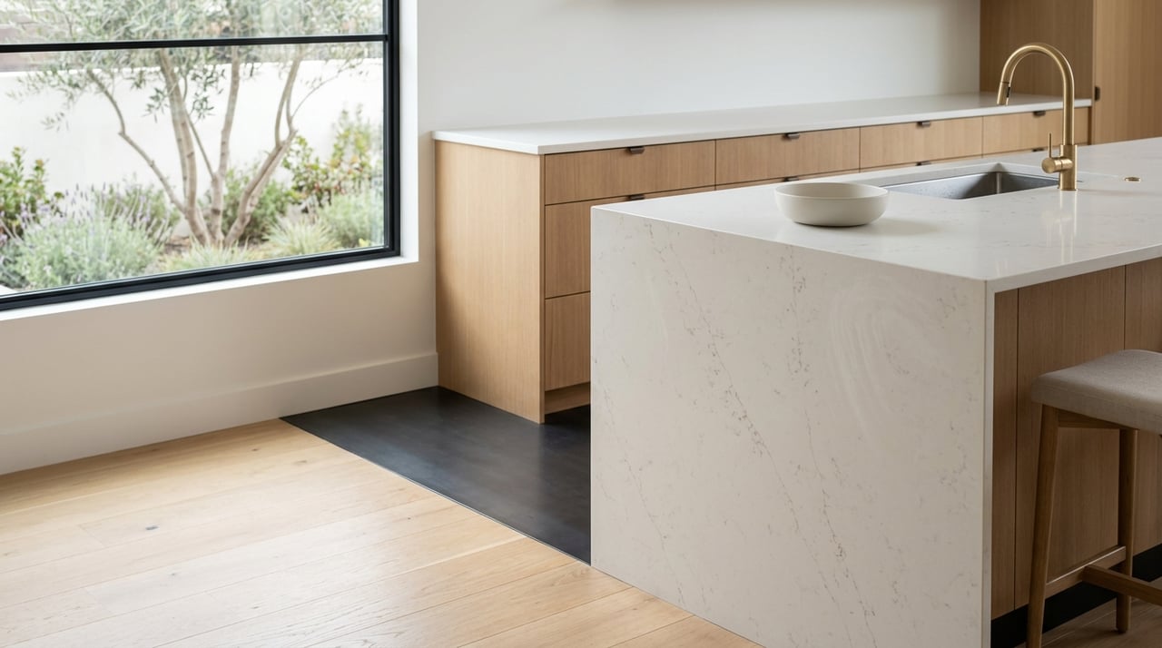 Kitchen island with honed quartz countertop, oak cabinetry, brass faucet, and soft courtyard planting.