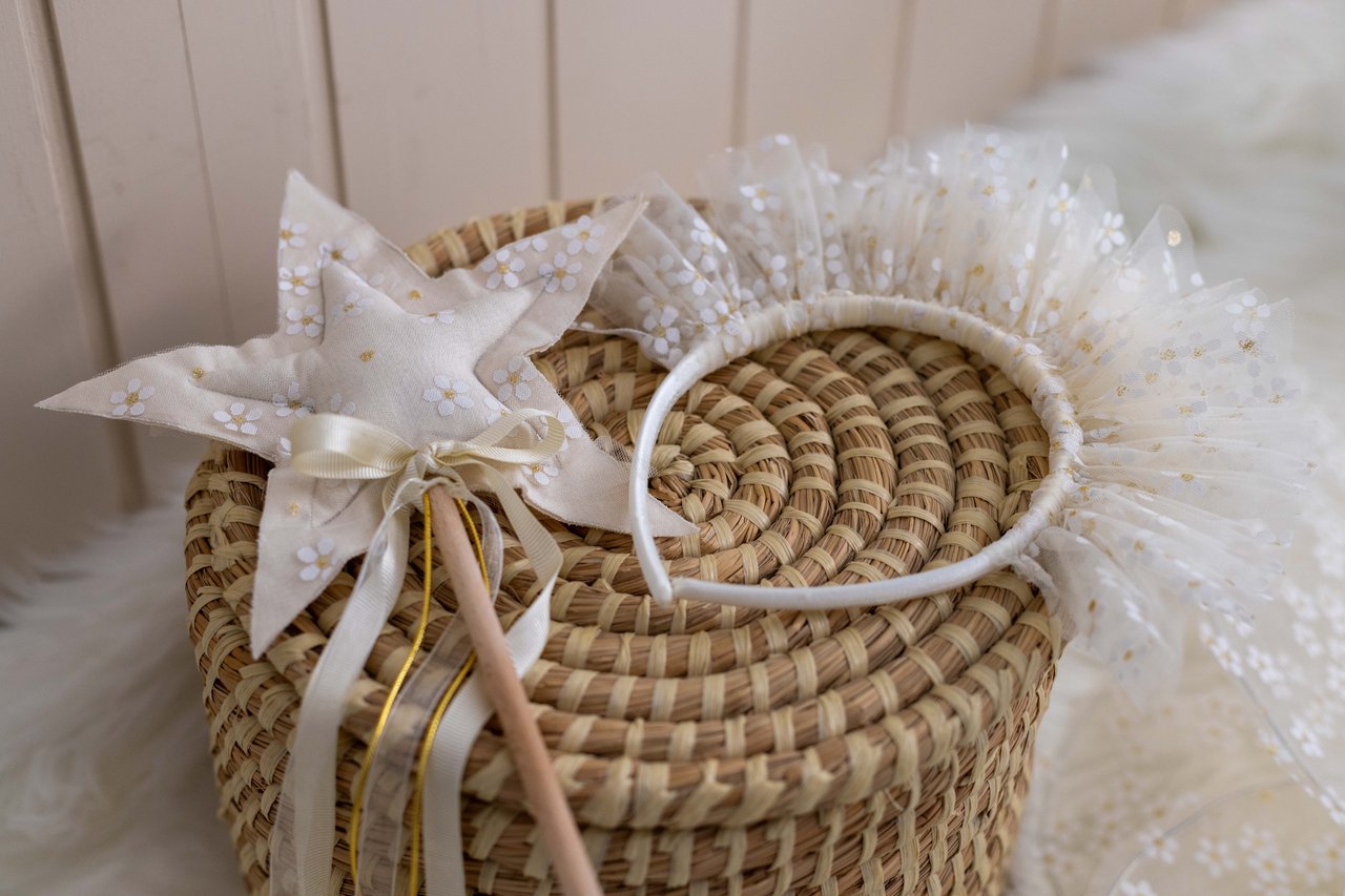 Woven basket with a white floral tulle headband and matching ribboned fabric accessory.