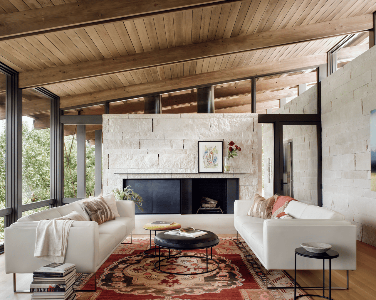 Lunaroya living room with a stone fireplace, timber ceiling, and white sofas.