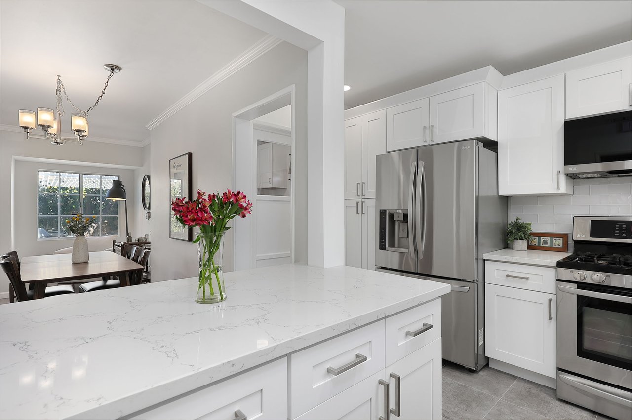 View from remodeled kitchen into dining space, showing open flow and staging at 17049 Baltar St