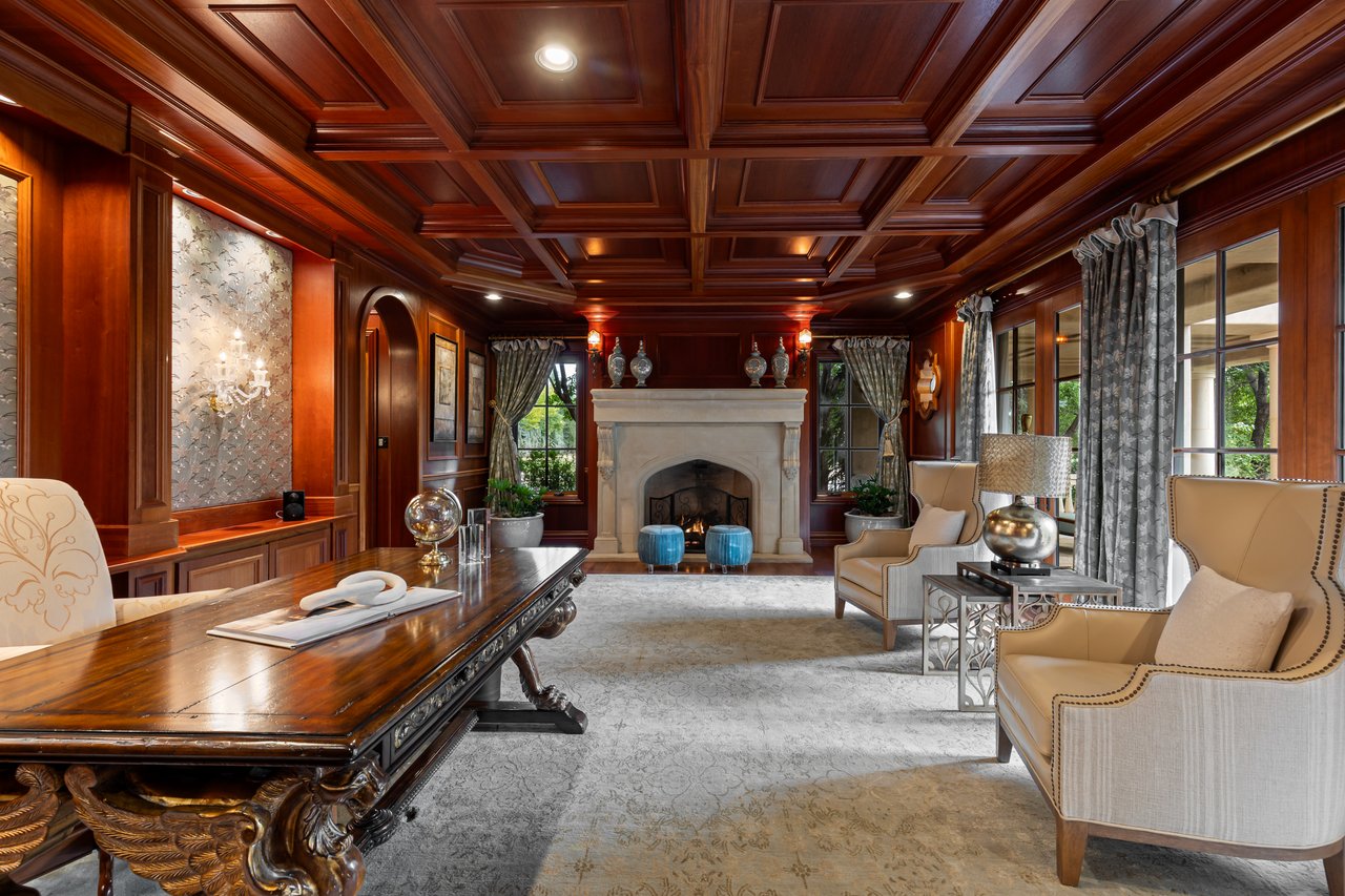 Formal living room with a coffered wood ceiling, stone fireplace, and carved desk.