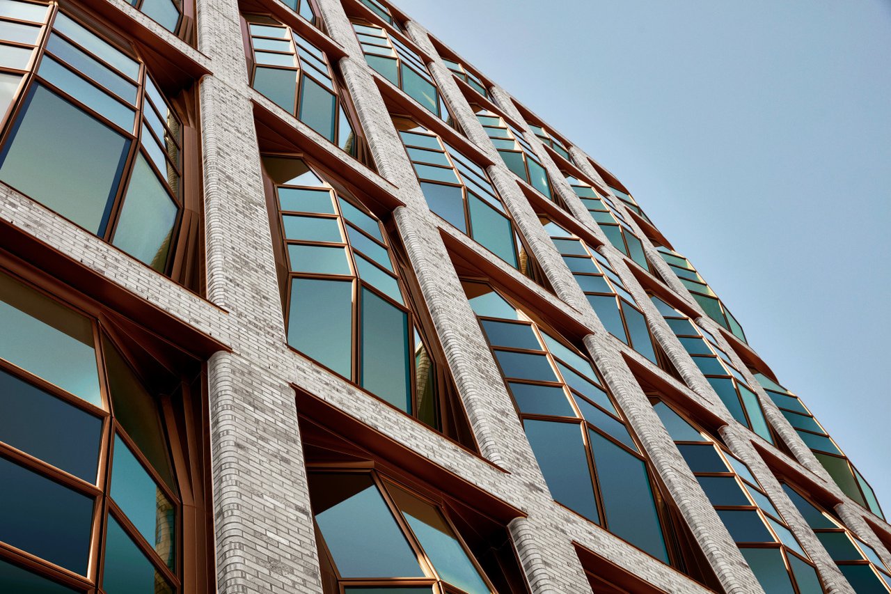 Lantern House’s curved facade with pale brick columns and copper-framed windows.