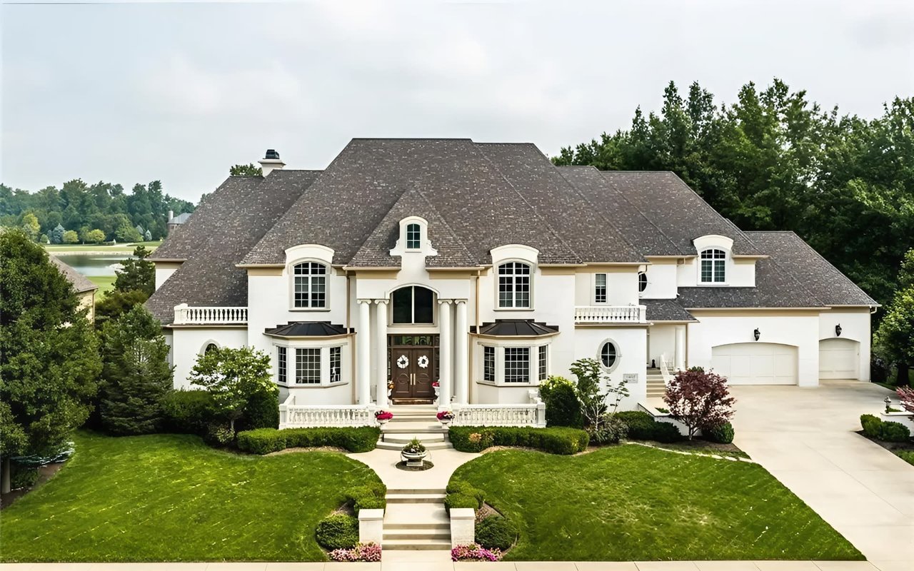 A sprawling European-inspired luxury residence showcasing classic architectural details, including multi-pane windows, bay windows, stone balustrades, a three-car garage, and exceptional estate-level curb appeal.