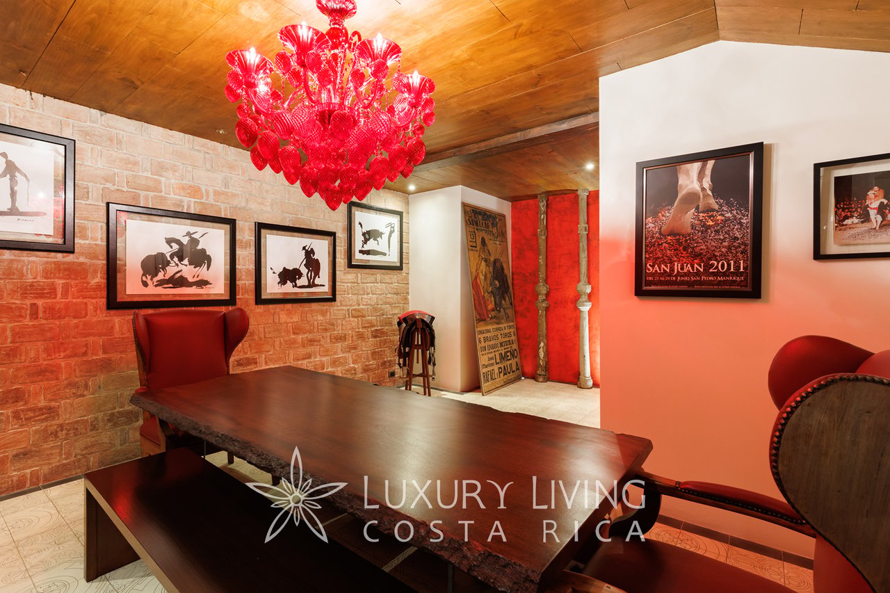 Dining room with a dark wood table, brick wall, and red glass chandelier.