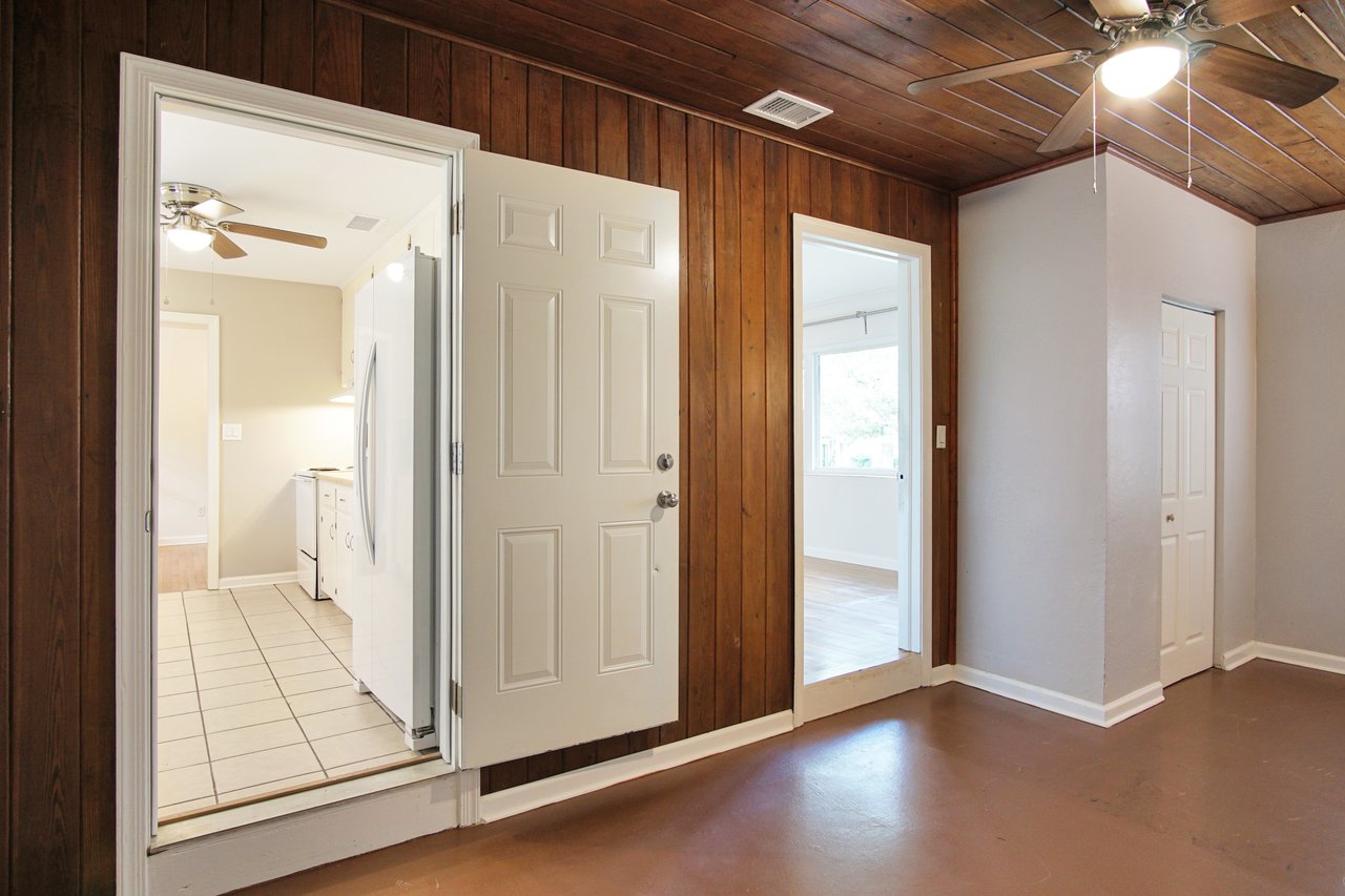 A room featuring a ceiling fan and a door, showcasing a simple and functional interior design.