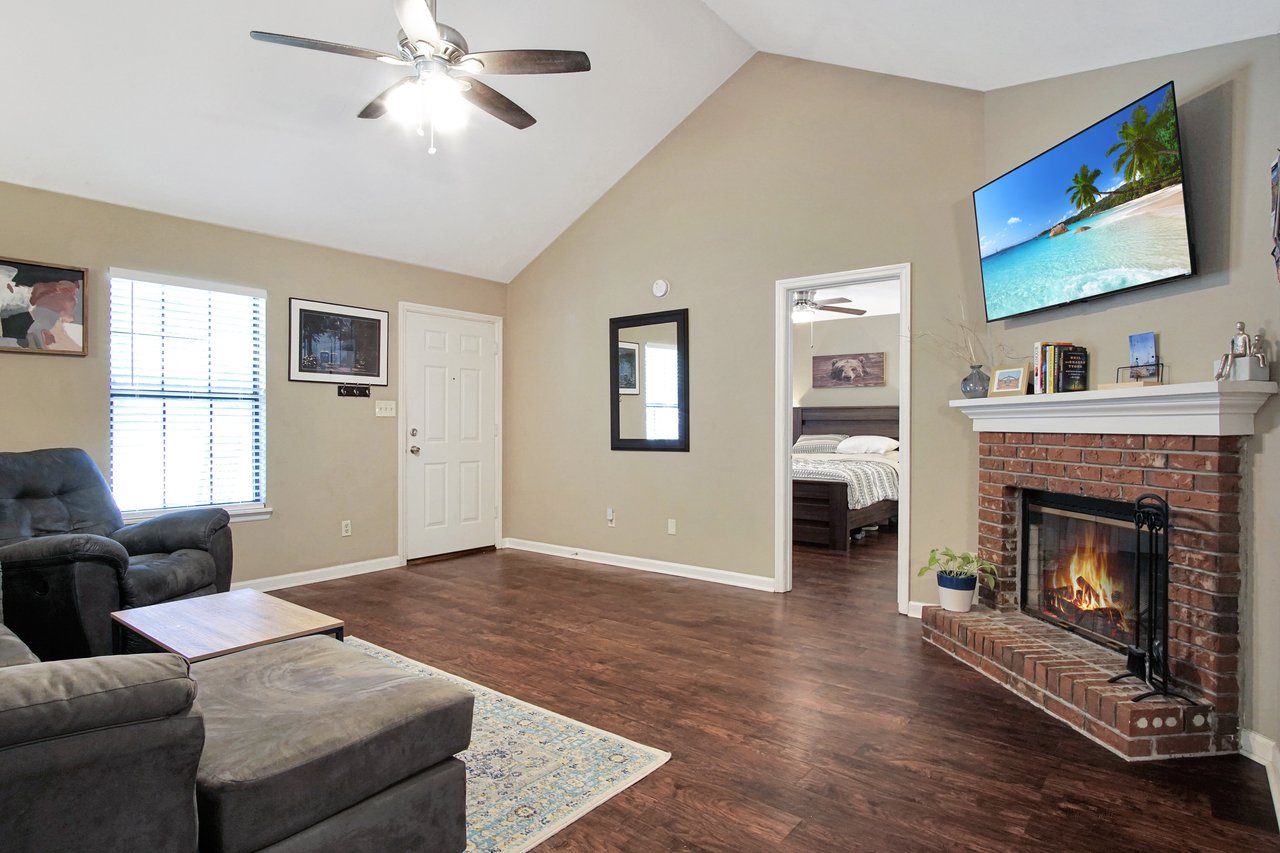 A cozy living room featuring a fireplace and a flat-screen TV, creating a warm and inviting atmosphere.