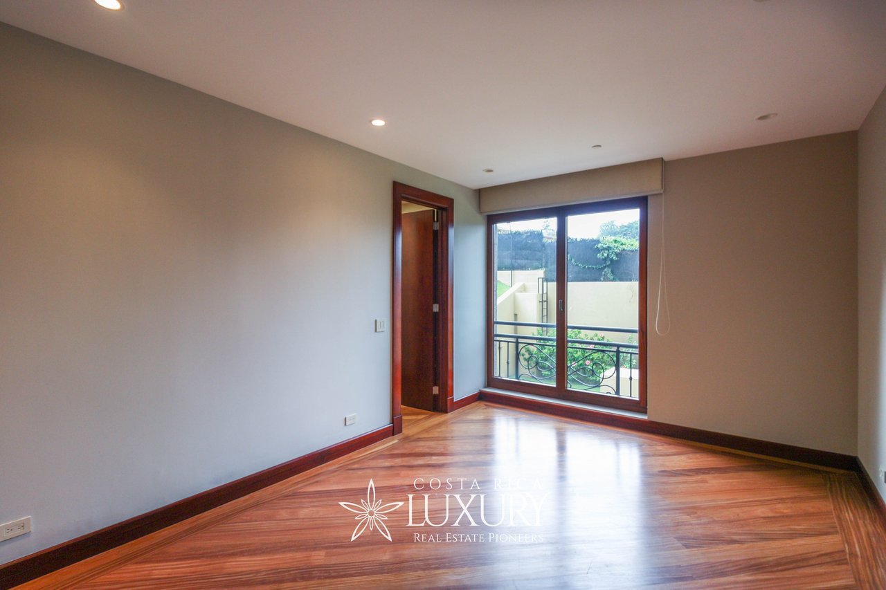 Empty apartment room with polished wood floors and a sliding glass door opening onto a balcony.