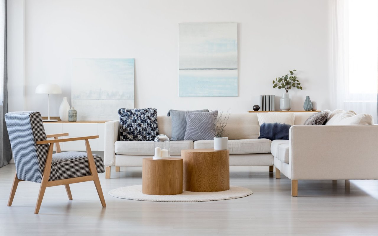 Bright living room with a white sectional, patterned chair, and pale wood coffee tables.