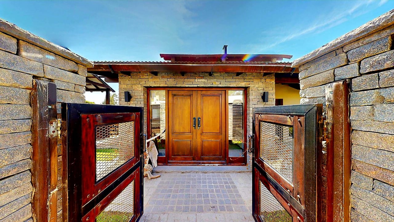Stone home entrance with open wooden gates and paneled double doors.