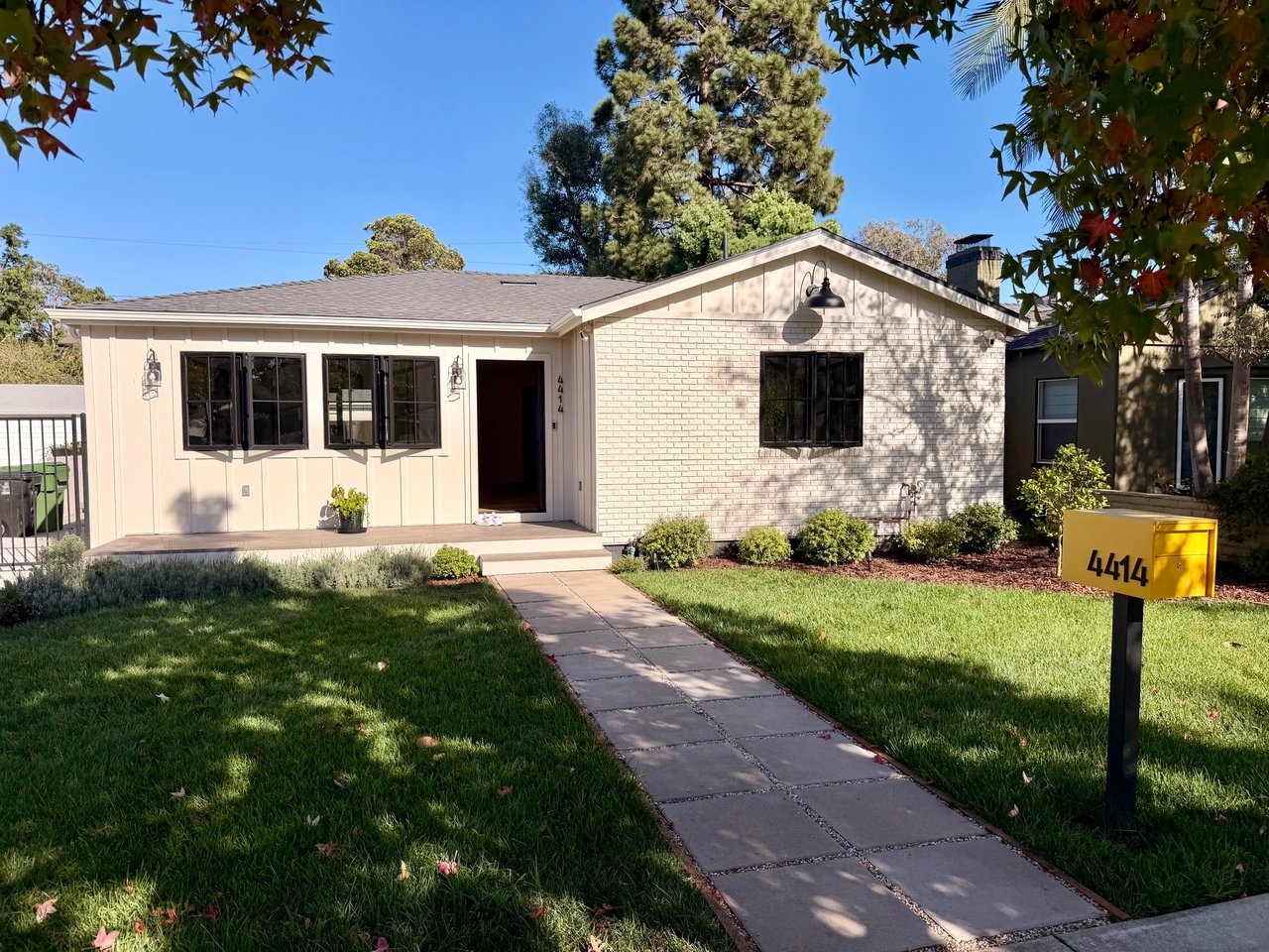 Single-story house with a brick gable, front lawn, paved walkway, and yellow mailbox marked 4414.