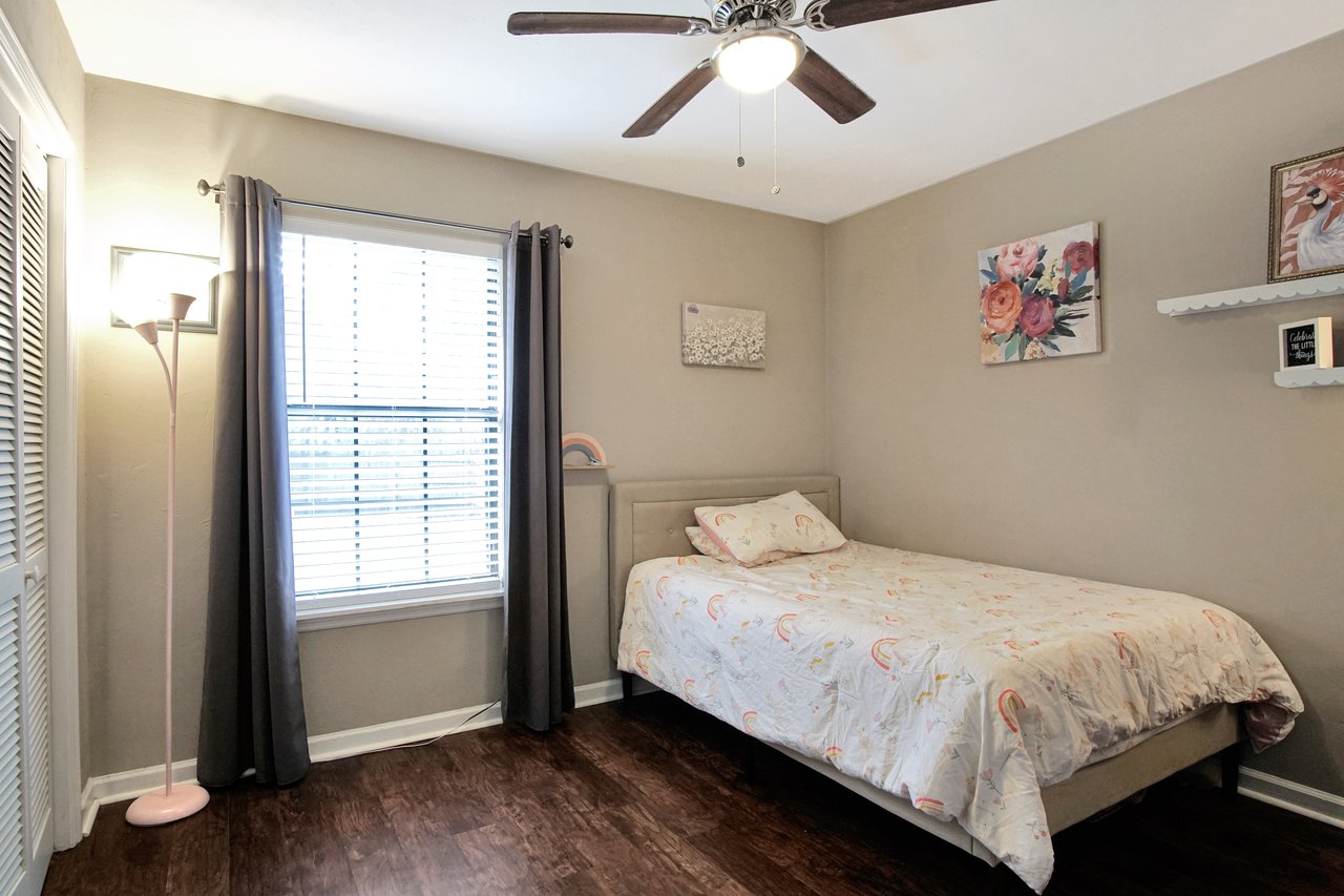 A cozy bedroom featuring a ceiling fan above a neatly made bed, creating a comfortable and inviting atmosphere.