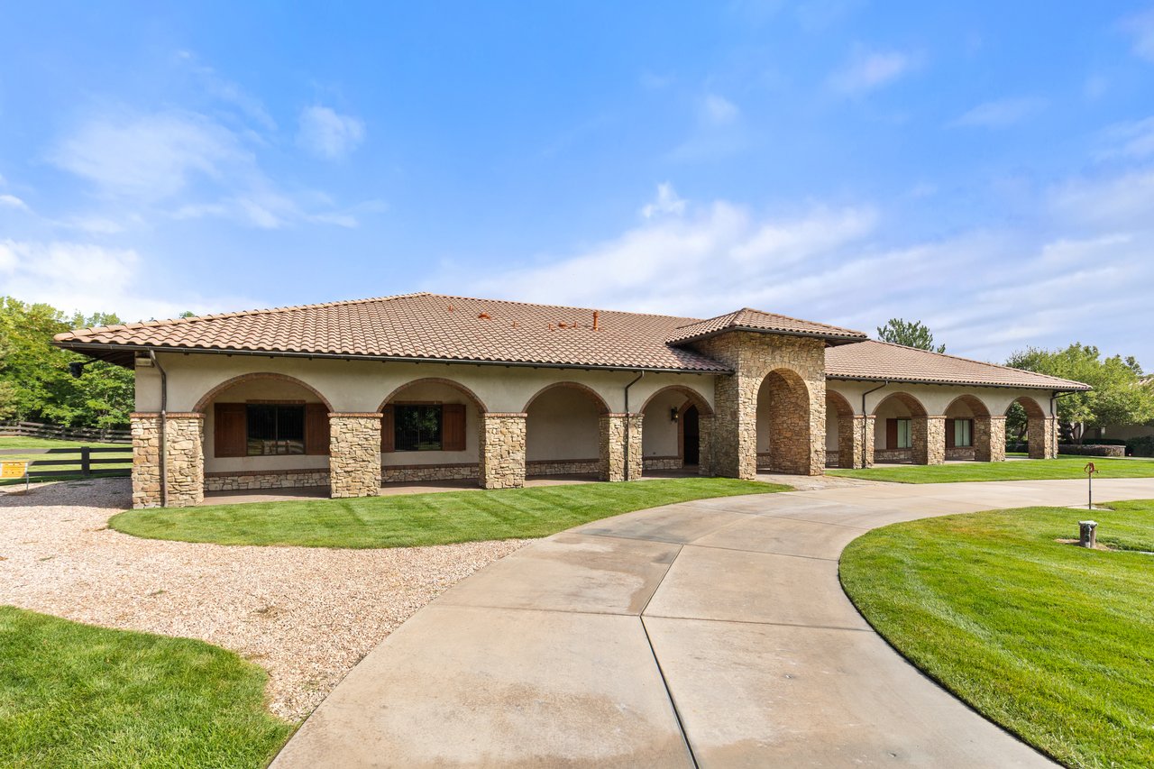 Single-story home with stone arches, a tile roof, and a curved concrete driveway.