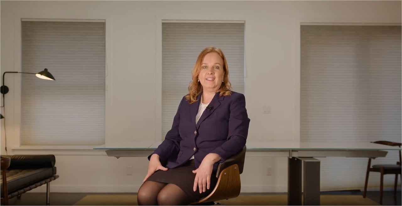Susan Holman seated in an office, wearing a navy blazer.