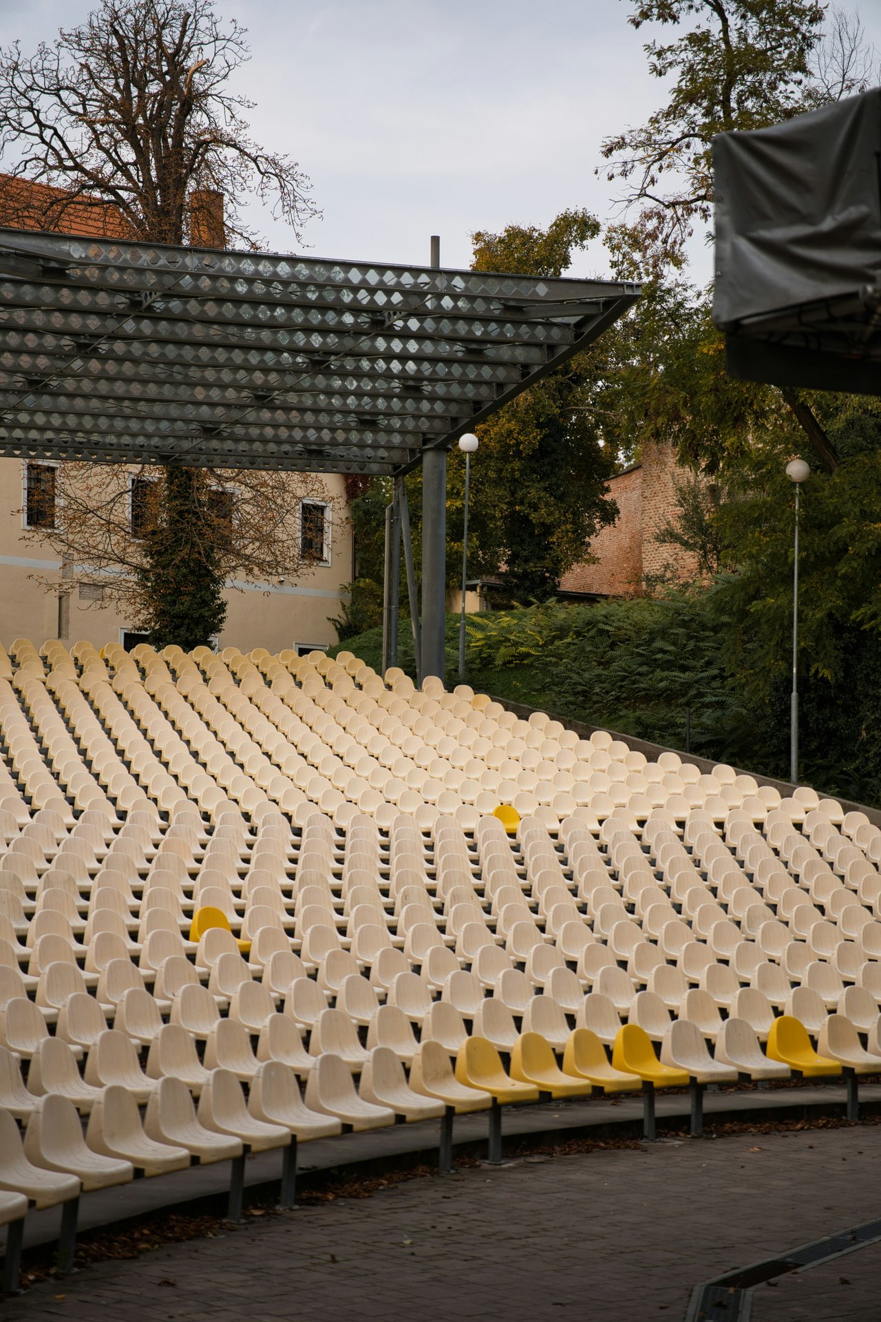 Rows of empty white and yellow seats at a proposed outdoor amphitheater with trees in the background