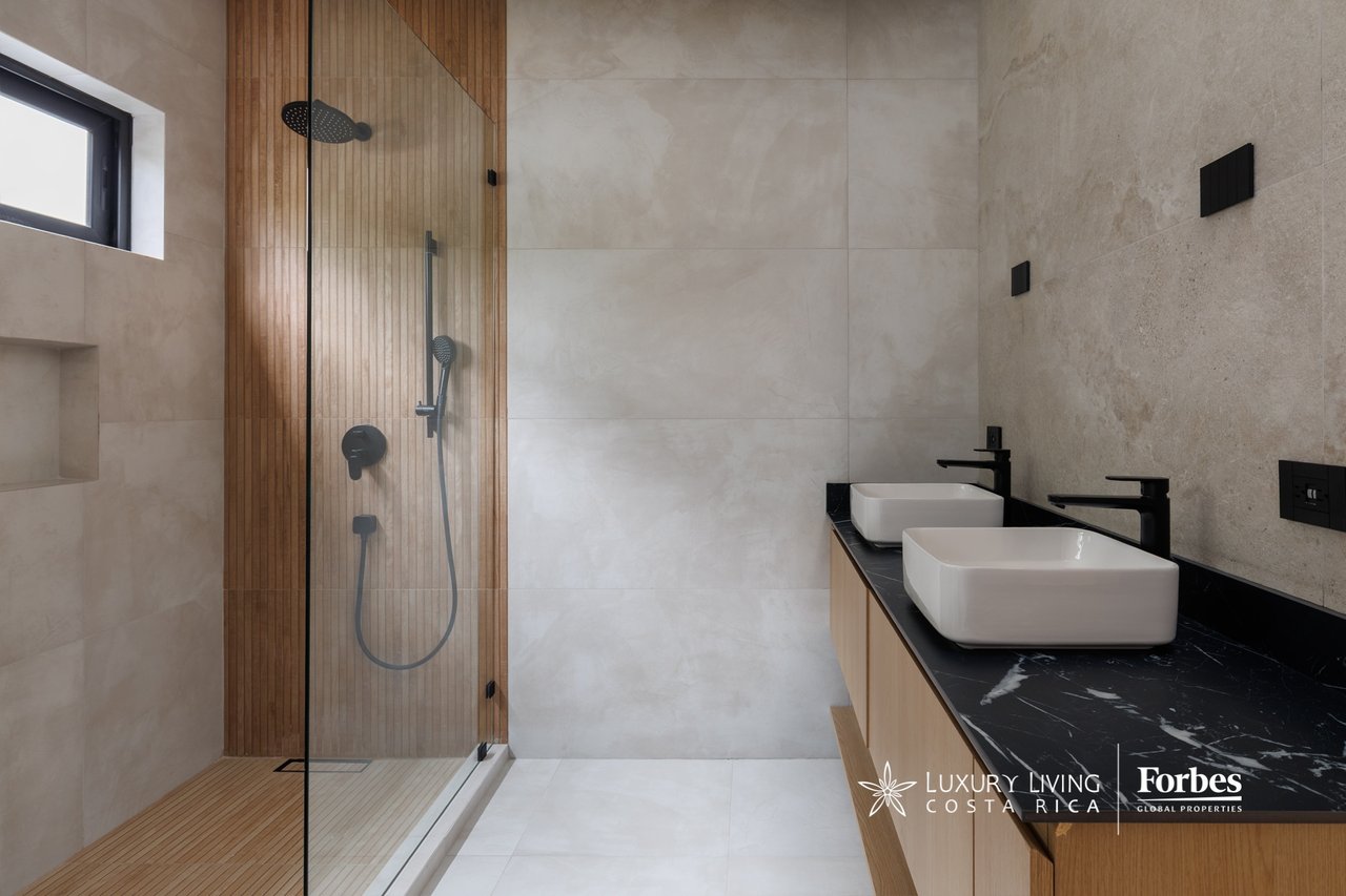 Modern bathroom with a wood-slat shower and double vessel sinks on a black marble vanity.