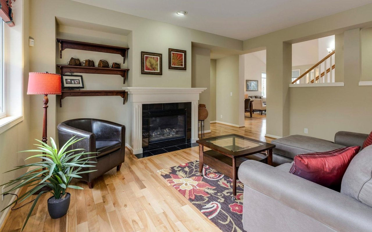 A brightly lit living room with light-colored hardwood floors and beige walls.