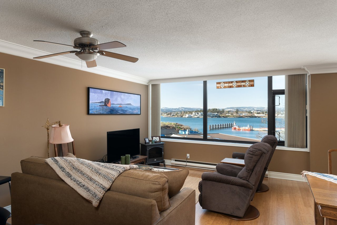 Bright living room featuring large windows, panoramic water views, and a comfortable seating arrangement.