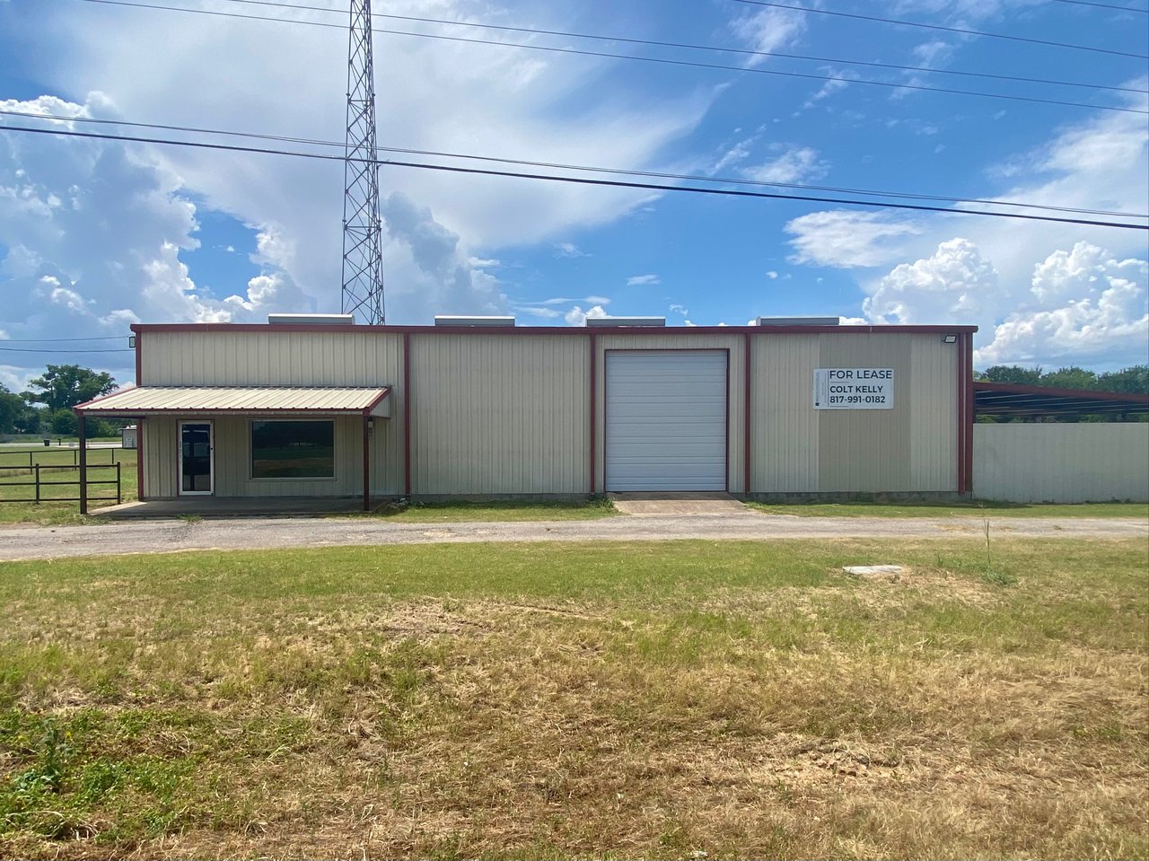 Beige metal commercial building with a roll-up door, office entrance, and for-lease sign.