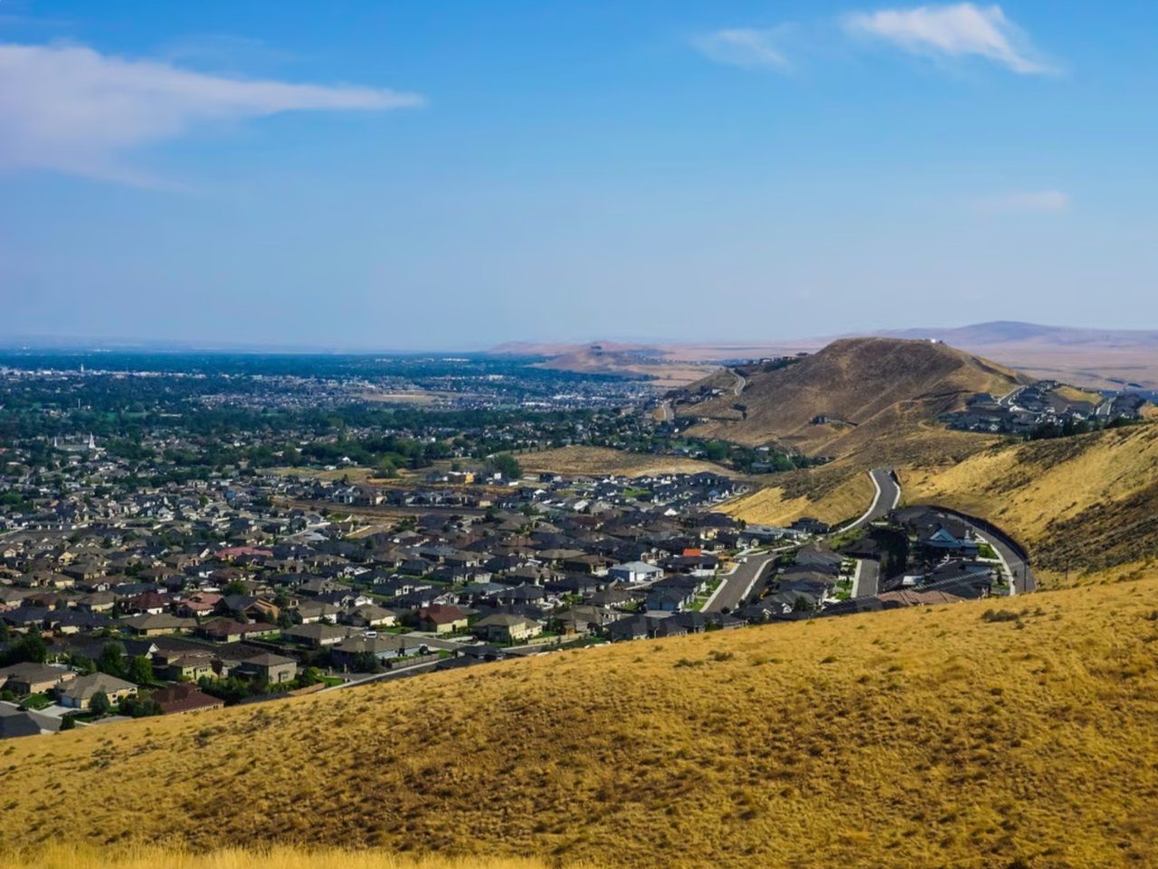 Aerial view of Tri-Cities, Washington neighborhood with homes, hills, and river valley.