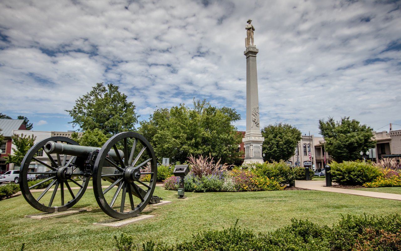 Historic cannon and statue-topped monument in a landscaped Franklin town square.