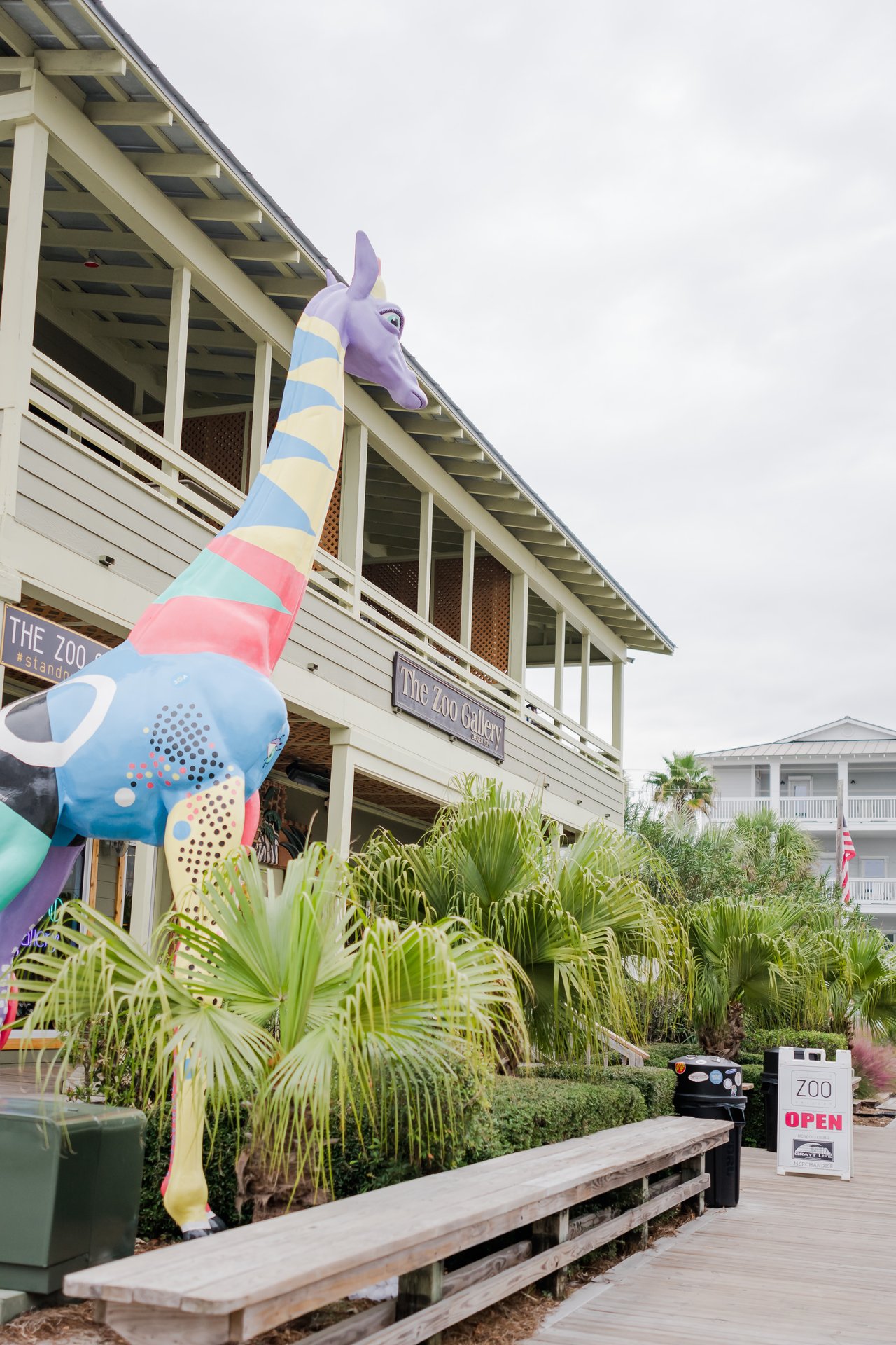 Whimsical multicolored mosaic giraffe climbing the weathered-wood facade of The Zoo Gallery in Grayton Beach on 30A, Florida