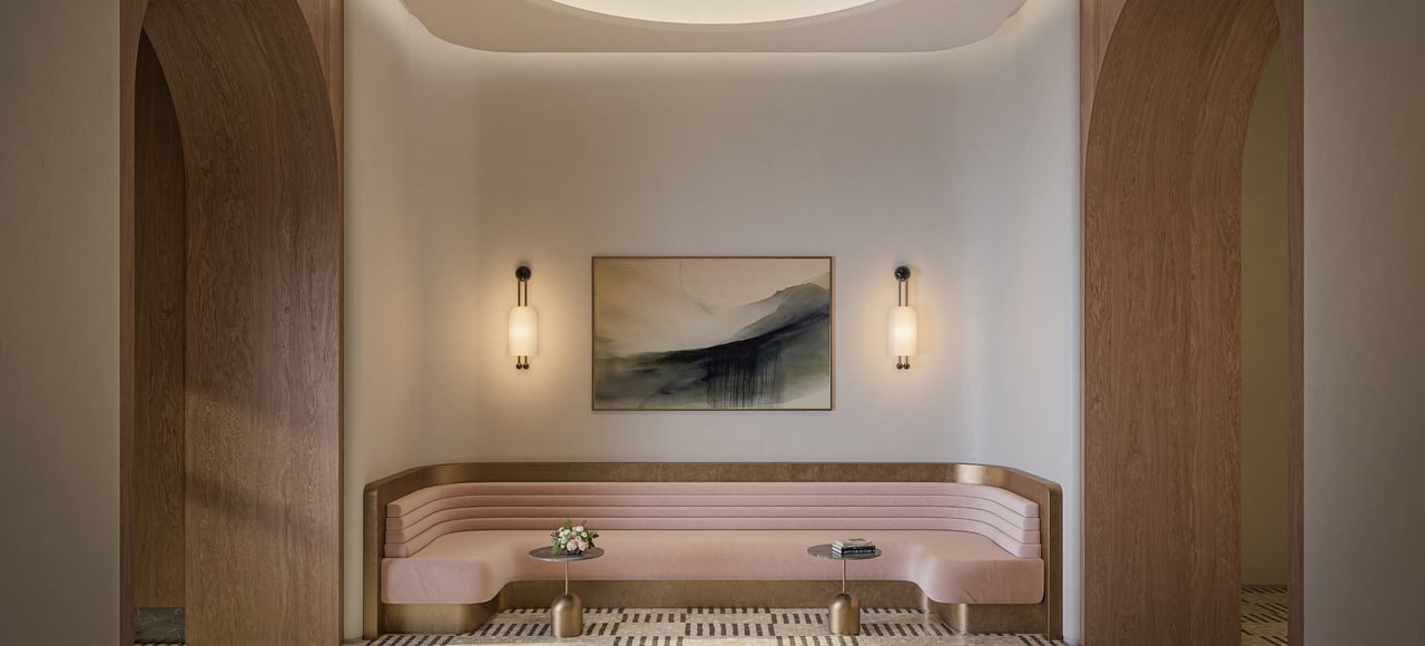 Lobby alcove with a curved pink banquette framed by wood arches and wall sconces.