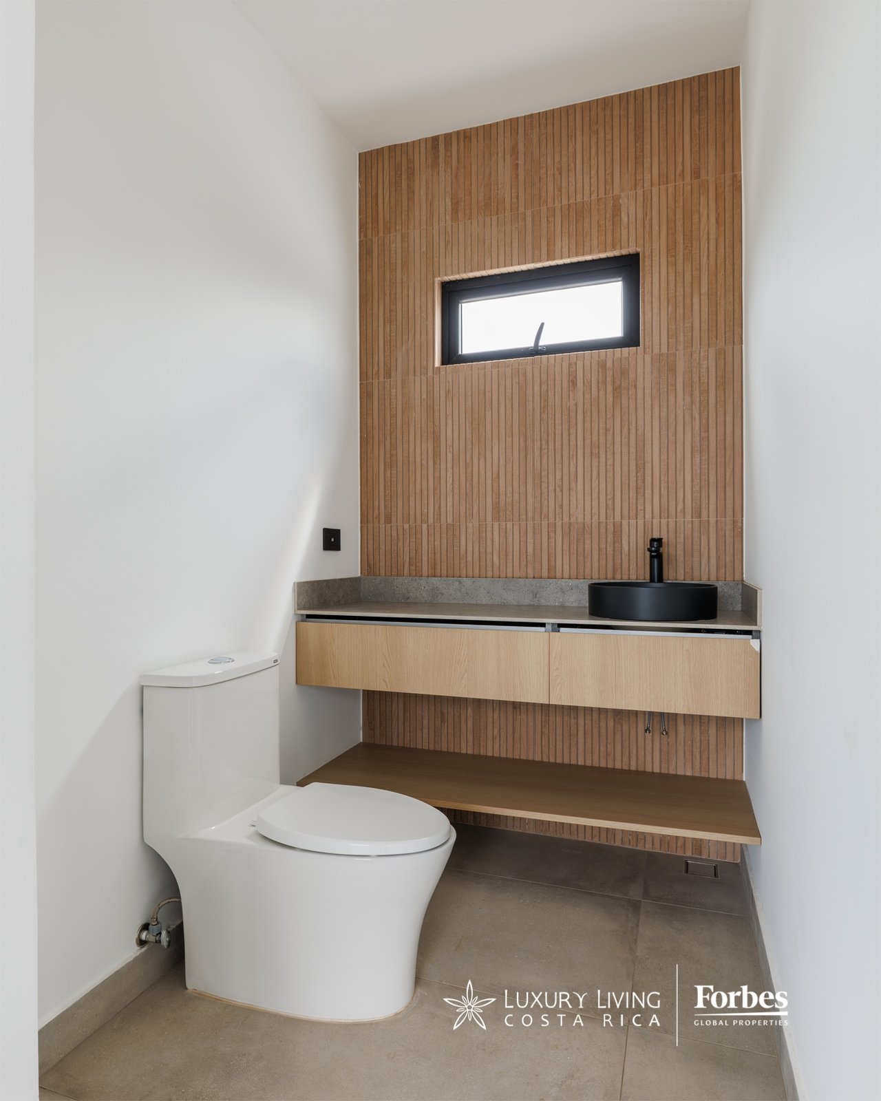 Modern bathroom with a floating wood vanity, black vessel sink, and vertical wood-look tile wall.