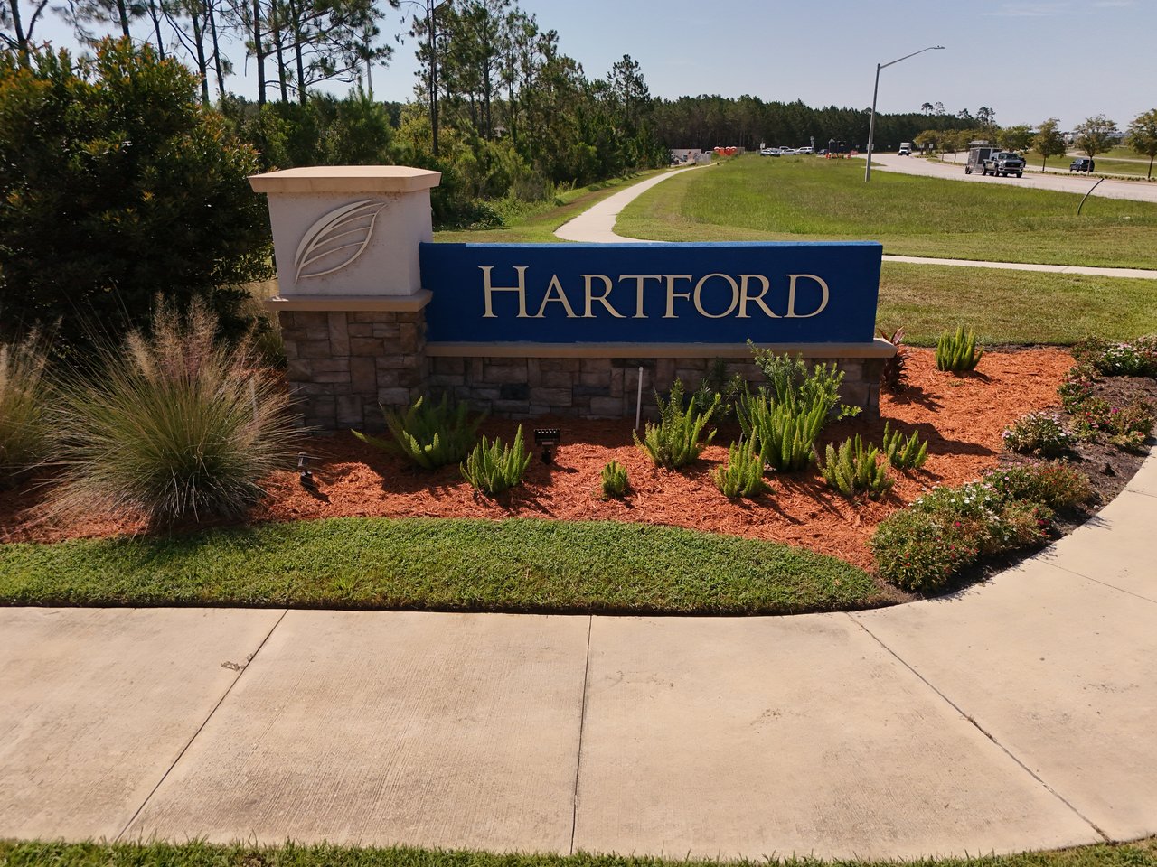 Hartford neighborhood entrance sign amid landscaped beds beside a sidewalk and road.