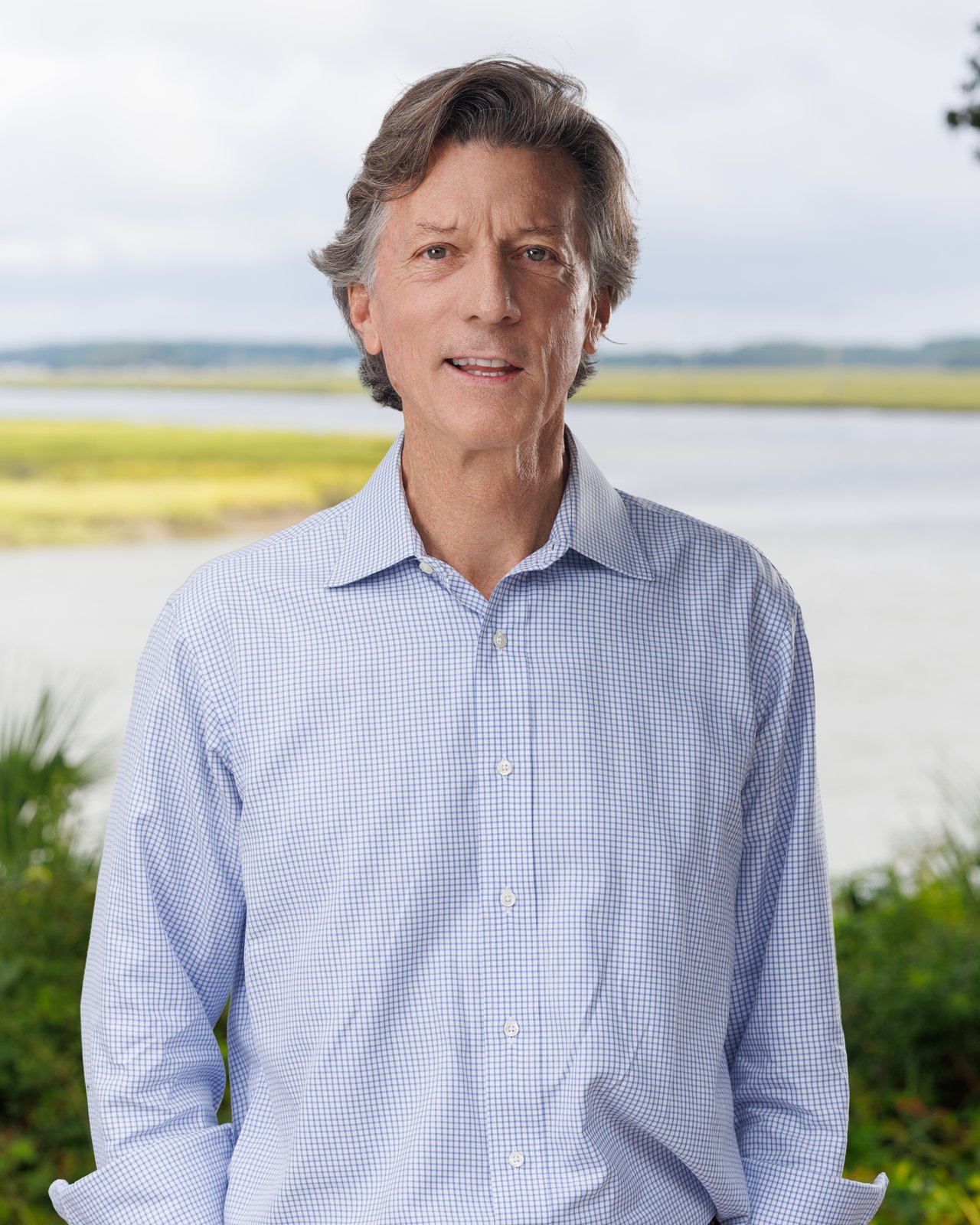 Rutledge Livingston in a blue-and-white checked shirt, with a marsh and waterway behind him.