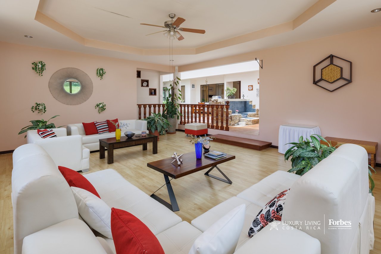 Furnished living room with white sofas, red accent pillows, and an adjoining courtyard.